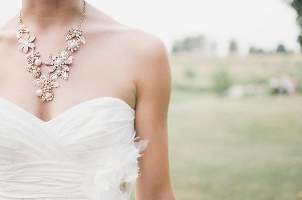 Heirloom Jewelry: Timeless Treasures Passed Down with Love 2 A close-up of a bride wearing a Heirloom Jewelry with strapless white dress adorned with an elegant floral necklace. The background is a soft, blurred outdoor scene